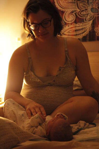 Newly postpartum mother gazing at new baby. Ready to settle in for rest.